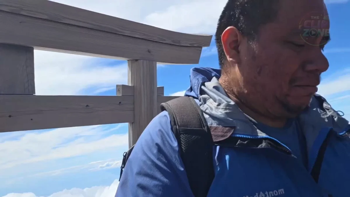 Hiker in blue jacket beside wooden mountain railing
