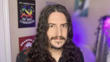 Long-haired man with beard poses indoors