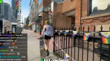 Person walking with skateboard past rainbow flags