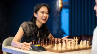 Woman smiling while playing chess at table