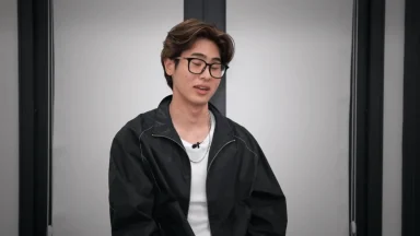 Person wearing glasses and black jacket indoors