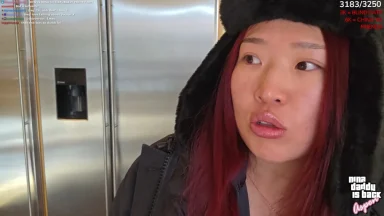 Person wearing winter hat indoors near refrigerator