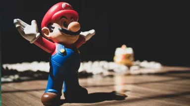 Mario figurine with arms raised on wooden floor