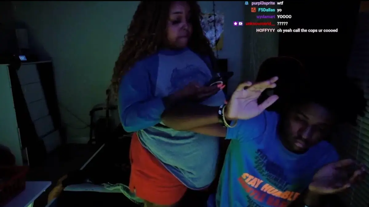 Two people gesture during a dimly lit livestream