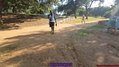 People walking on dirt path in park with trees.