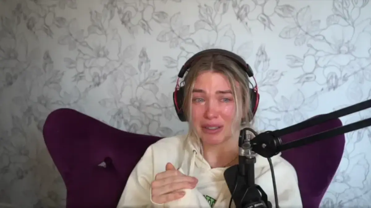 Person crying while streaming with microphone and headphones.