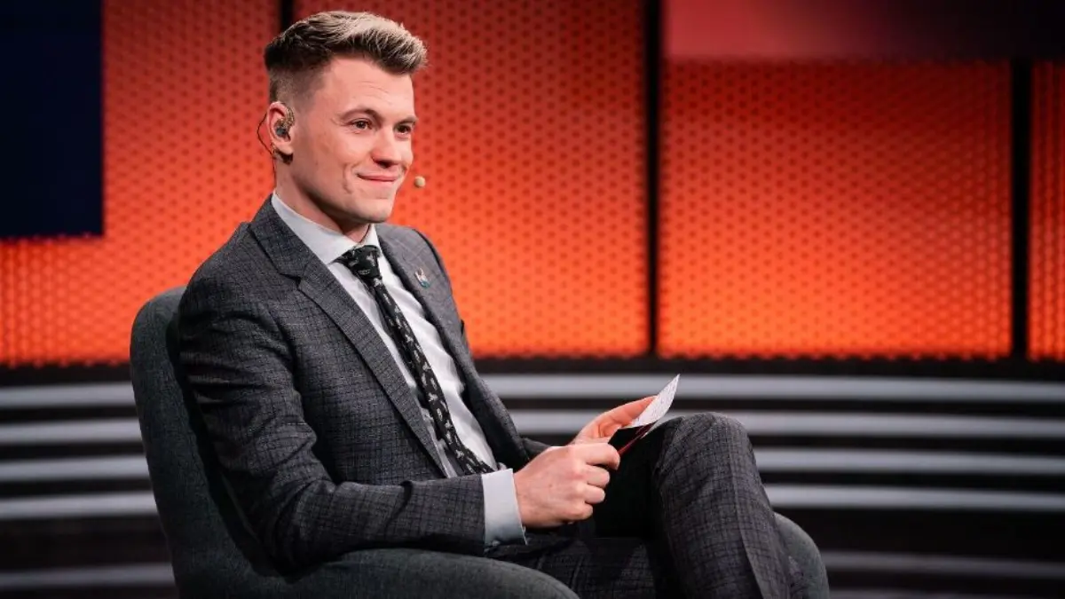 Man in suit hosting talk show on stage