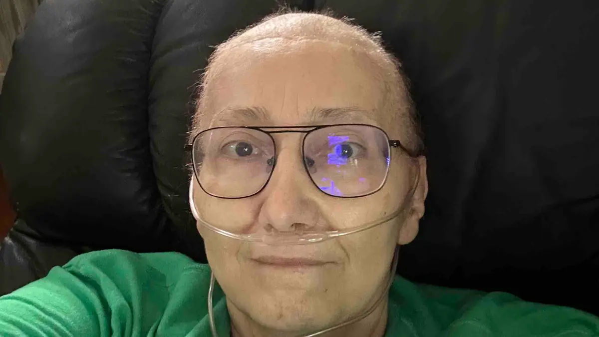Person wearing glasses and oxygen tube smiling