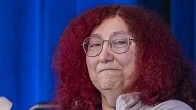 Person with curly red hair smiling on stage