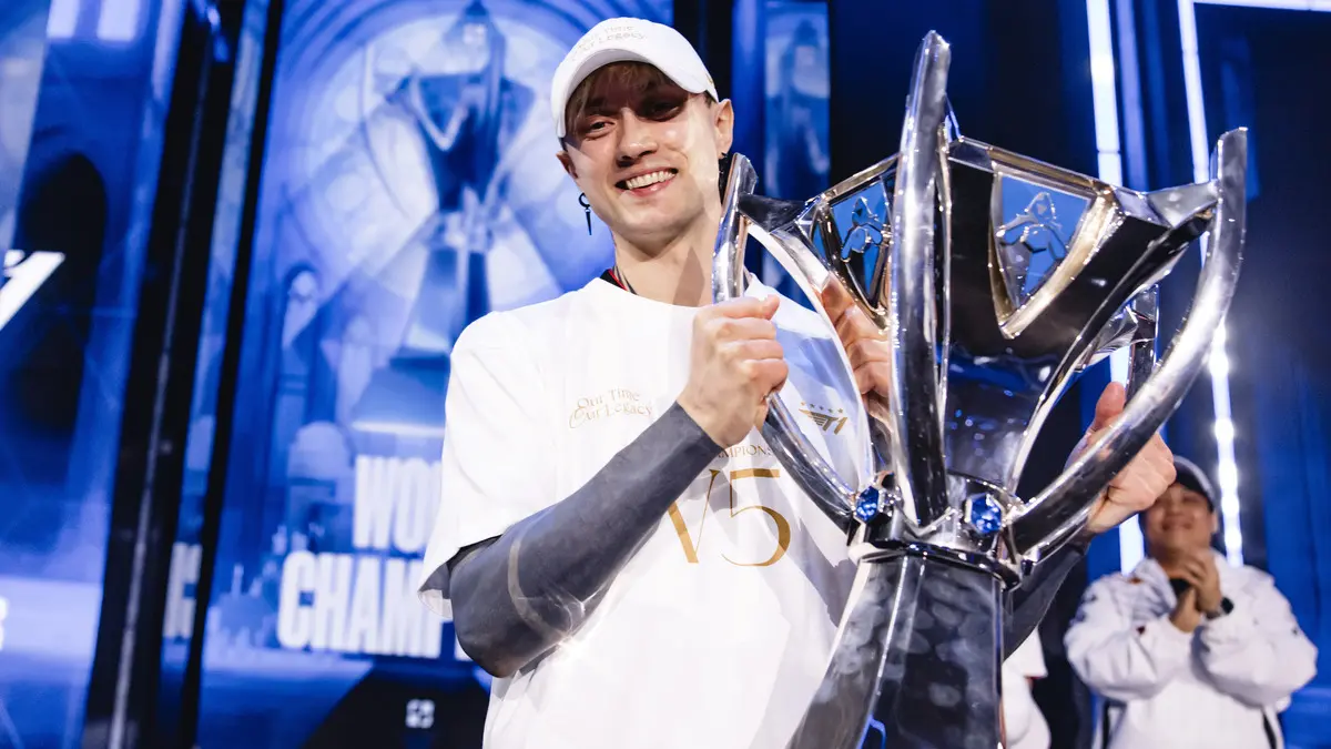 Esports champion holding large silver trophy on stage
