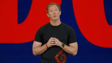 Man speaking on stage with red background