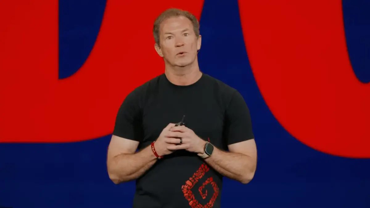 Man speaking on stage with red background