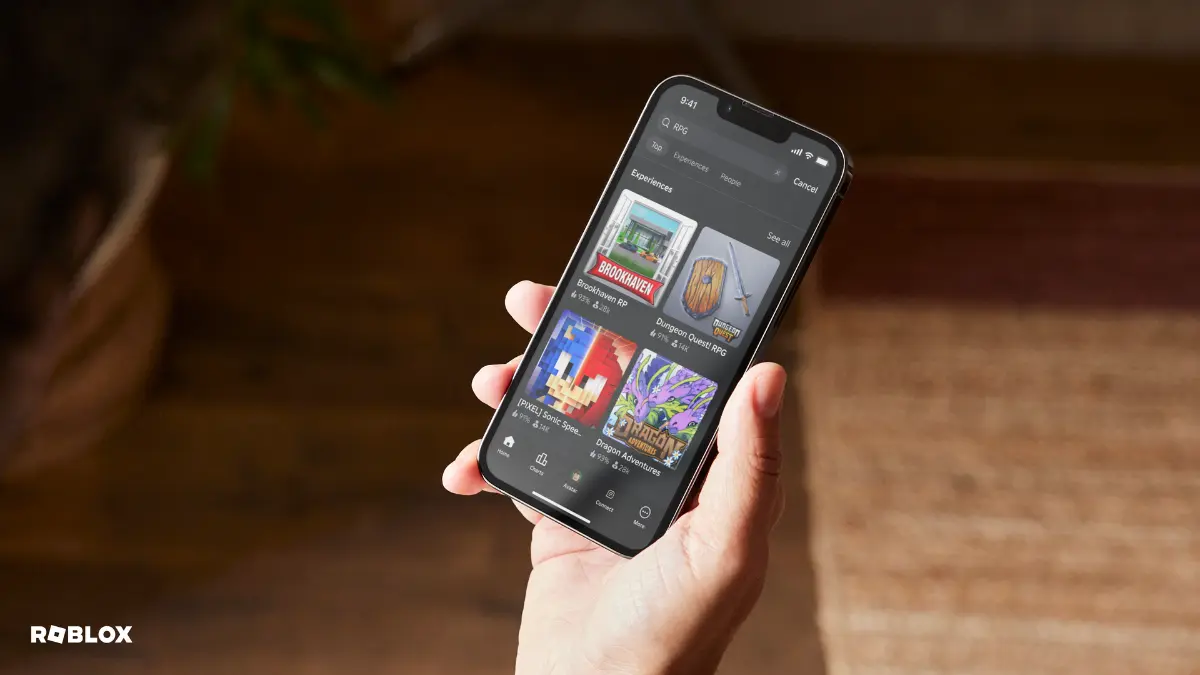 roblox predator problem verifying age Hand holding smartphone displaying Roblox game menu.