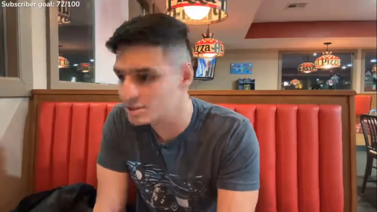 Man sitting in red booth at pizza restaurant