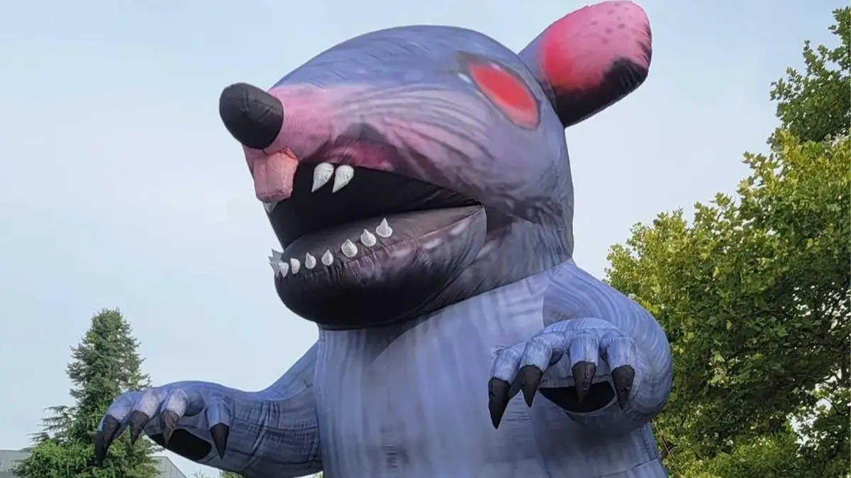 Giant purple inflatable rat with sharp teeth outdoors