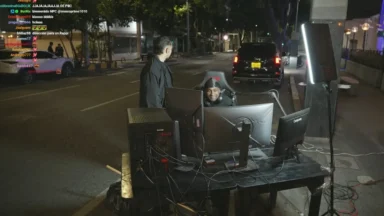 Nighttime street livestream setup with multiple monitors and lighting