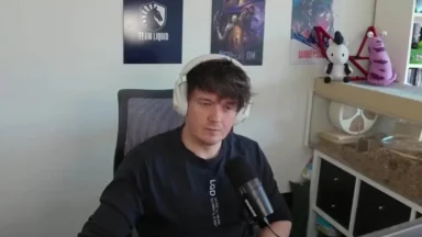 Headset-wearing streamer speaks into microphone in gaming room.
