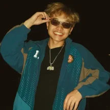 Smiling person wearing sunglasses and a blue jacket