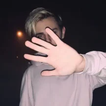 Person raising hand toward camera at night