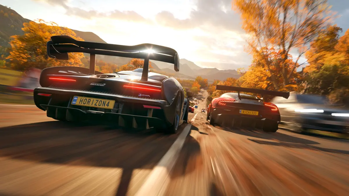 Sports cars racing on autumn road at sunset.