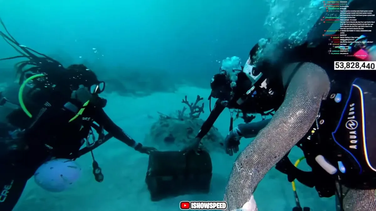 Two scuba divers examining chest underwater