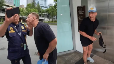 Man confronts security guard outdoors.