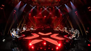 Esports teams compete on a red-lit arena stage.