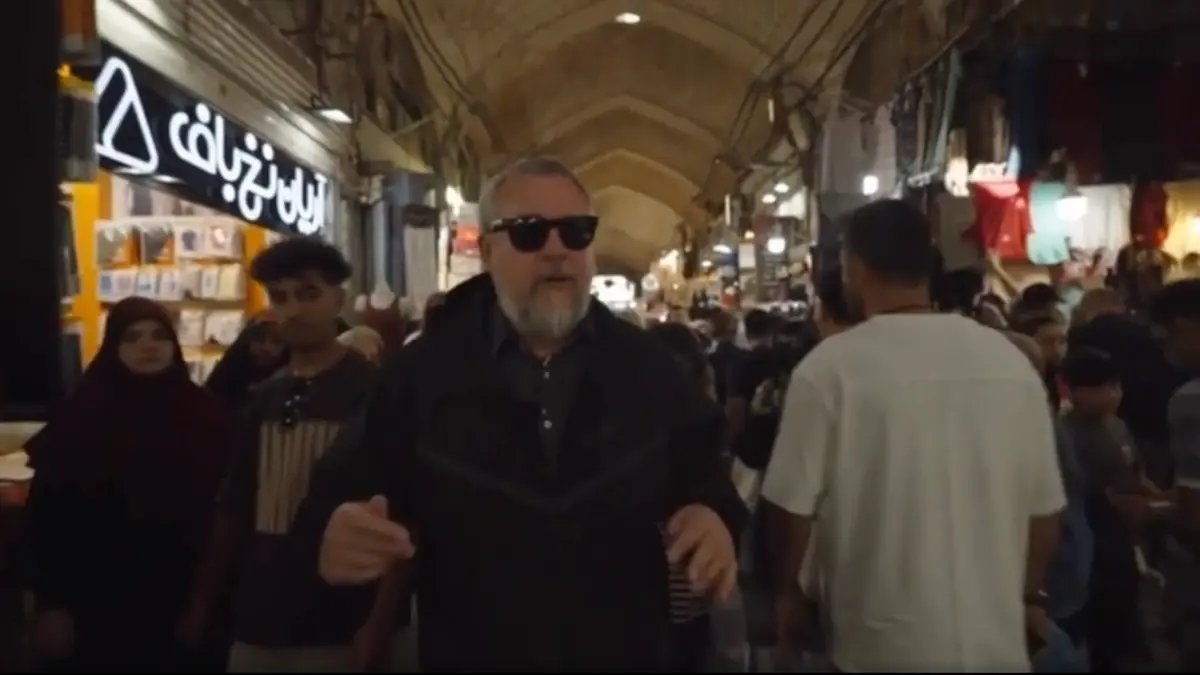 Man in sunglasses walking through crowded indoor market
